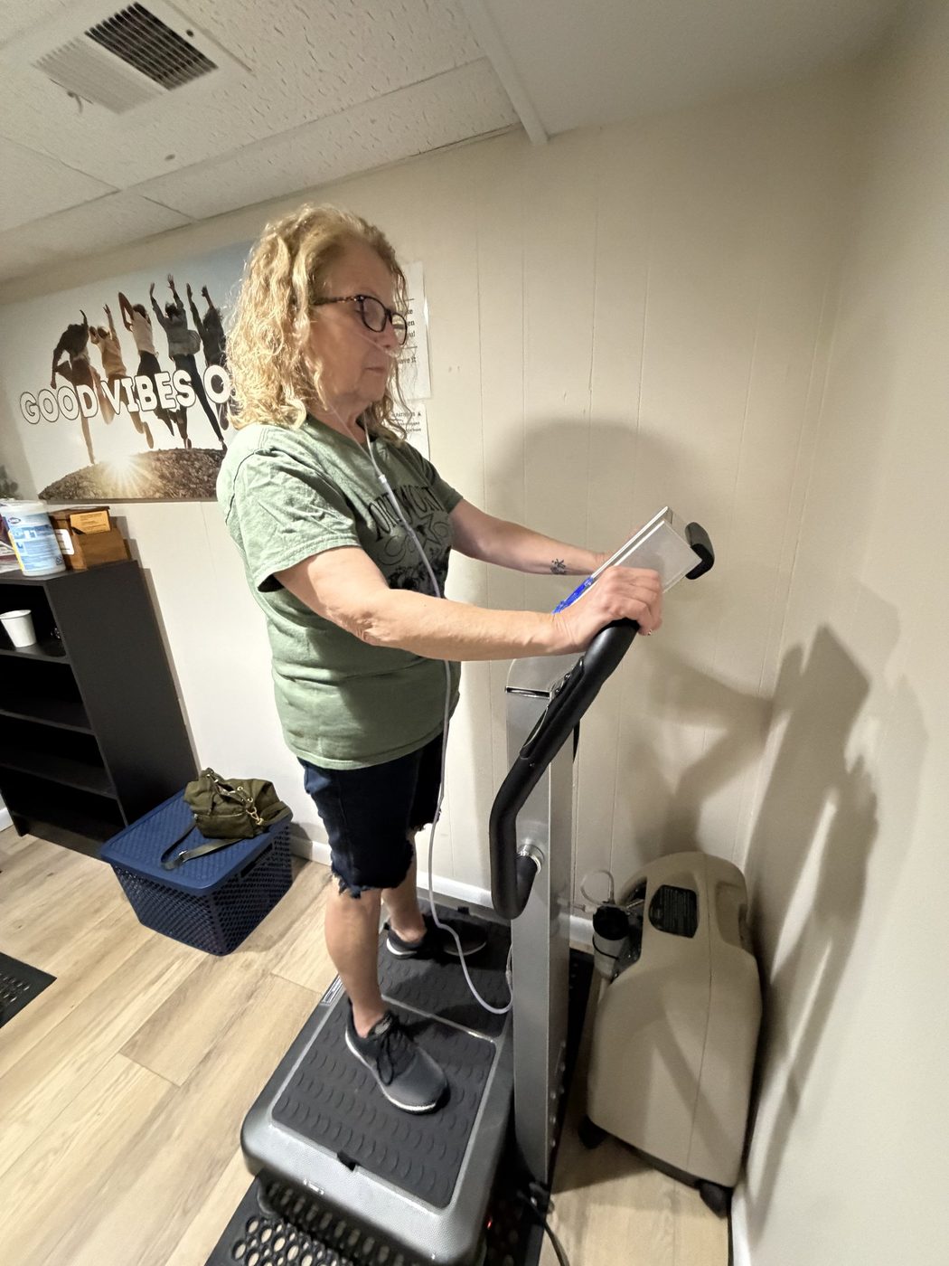 EWOT setup with a stationary exercise bike, portable oxygen concentrator, and clear tubing leading to a mask on the handlebars.